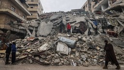 Menschen betrachten die Trümmer eines zerstörten Wohnhauses (Syrien, Idlib, 06.02.2023)