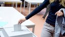 Symbolbild: Ein junger Mensch wirft einen Wahlschein in eine Wahlurne.