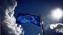 EU-Flagge vor Himmel mit Wolken und Sonne