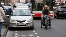 Symbolbild: Radfahrerin weicht wegen Falschparker vom Radweg auf die Fahrbahn aus