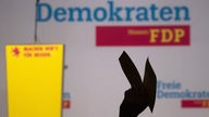 Hand hält Zettel hoch bei FDP-Mitgliederversammlung