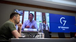 Wolodymyr Selenskyj vor der Übertragungsleinwand des G7-Gipfels mit Justin Trudeau im Bild