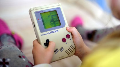 Ein Kind spielt auf einem originalen Game Boy das Spiel Tetris