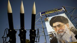 Drei Flugabwehrraketen vom Typ SAM 6 neben einem Riesenposter von Ayatollah Ali Khamenei.