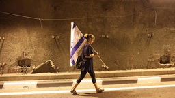 Eine Demonstrantin hält eine israelische Flagge während sie an einem Protest gegen die Justizreform teilnimmt (Tel Aviv, 27.07.2023).