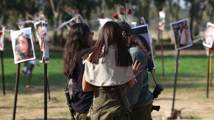 Junge Israelis stehen vor Bildern von Menschen, die während des Supernova-Musikfestivals am 7. Oktober von Hamas-Kämpfern gefangen genommen oder getötet wurden.