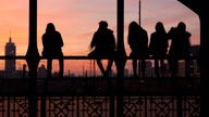 Symbolbild: Gegenlichtaufnahme von Jugendlichen auf einem Brückengeländer