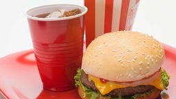 Symbolbild: Ein Cheeseburger und eine Cola auf einem Tablett.