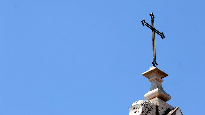 Symbolbild: Ein christliches Kreuz auf einem Kirchturm in Lissabon.