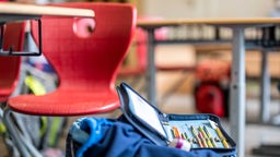 Symbolbild: Ein Schüleretui liegt auf einem Rucksack in einem Klassenzimmer.