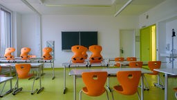 In einem leeren Klassenzimmer stehen die Stühle auf den Tischen