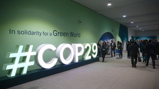 Während der COP29 laufen Menschen an einem COP29-Logo vorbei, Baku, Aserbaidschan.