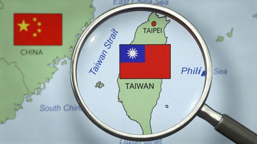 Symbolbild zum Thema Konflikt zwischen China und Taiwan. Blick durch eine Lupe auf Taiwan.