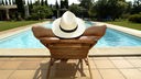 Symbolbild: Ein Mensch liegt entspannt in einem Liegestuhl am Pool