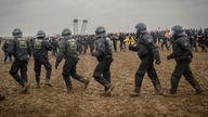 Polizisten und Aktivisten im matschigen Feld