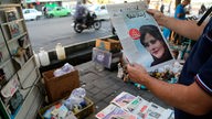 Ein Mensch hält eine Zeitung in der Hand, auf deren Titelblatt Mahsa Amini zu sehen ist (Teheran 18.09.2022)