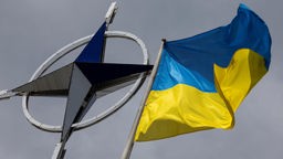 Eine ukrainische Nationalflagge weht vor dem NATO-Emblem.