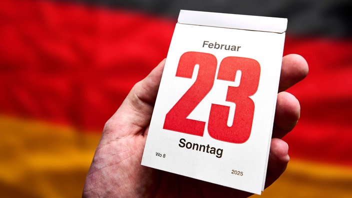 Symbolbild: Kalender mit der Aufschrift "23. Februar 2025" vor Flagge in Nationalfarben.