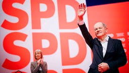 Olaf Scholz begrüßt mit erhobenem Arm das Publikum beim SPD-Parteitag am 11.01.2025.