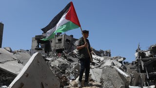 Palästinenser mit Palästinenserflagge auf einem Trümmerberg