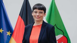 Josefine Paul vor Fahnen von der EU, der Bundesrepublik und NRW (2022)