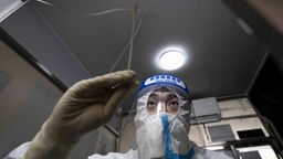 Ein Beamter in Schutzkleidung führt in Peking einen PCR-Test durch