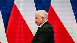 Seitenprofil von Jaroslaw Kaczynski vor polnischen Flaggen