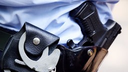 Ein Polizist mit Handschellen und Pistole am Gürtel steht in Köln