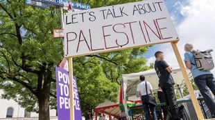 Pro-Palästinensisches Protestcamp vor einer Universität. Ein vor einem Infostand steht ein Plakat mit der Aufschrift: "Let's talk about Palestine". Archivbild: 16.05.2024