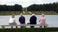 Symbolbild: Menschen mit grauen Haaren auf einer Bank am See.