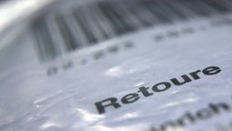 Das Wort «Retoure» steht auf dem Retourenaufkleber eines in Folie verpackten Päckchens, welches an einen Online-Versandhändler zurück geschickt werden soll.