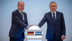 Bundeskanzler Olaf Scholz (SPD, l) drückt nach am Deutsch-Ukrainischen Wirtschaftsforum einen Buzzer neben Schawkat Mirsijojew, Präsident von Usbekistan, zur Eröffnung einer Usbekisch-Deutschen Verwaltungsschule (16.09.2024).