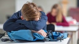 Symbolbild: Ein junger Mensch schläft im Unterricht