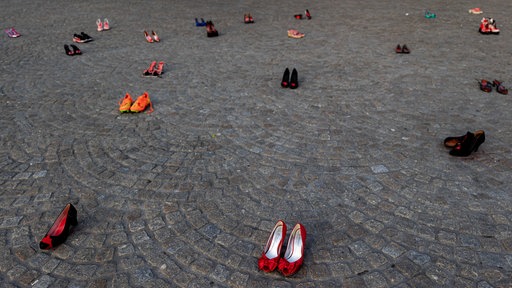 Auf einem PLatz stehen 44 Paare Damenschuhe, die mit roter Farbe befleckt sind. Teil einer Demonstration gegen Frauenmorde.