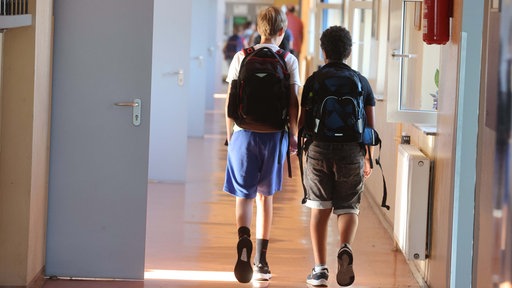 Jugendliche mit Schulrucksack in einem Schulflur.