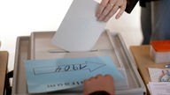 Wählerin gibt Wahlzettel ab