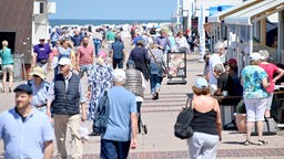 Menschen gehen über die Promenade von Westerland. Symbolbild