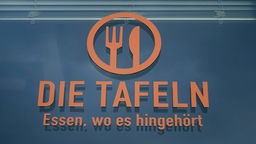 An einer Wand ist das Logo der Tafeln angebracht, unter diesem steht "Essen, wo es hingehört"