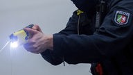 Ein Polizeibeamter demonstriert einen Schuss  mit einem Taser