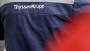 Ein Mensch trägt eine Werksuniform mit dem Aufdruck "ThyssenKrupp".