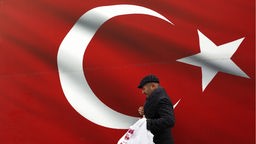 Ein Mann geht an einer türkischen Flagge vorbei. Symbolbild