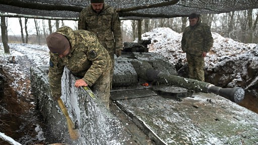 Ukrainische Soldaten beseitigen Schnee und Eis von einem Panzer (27.11.2023)
