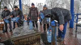 Archivbild: Nach einem Raketenangriff auf Kiew füllen Menschen Wasser an einer Pumpe in Plastikbehälter (24.11.2022)