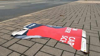 Zerissenes Wahlplakat der SPD liegt auf dem Gehweg