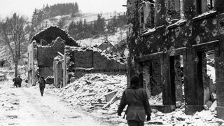 Soldaten auf den Straßen des verschneiten und zerbombten Houffalize, Belgien, im Januar 1945