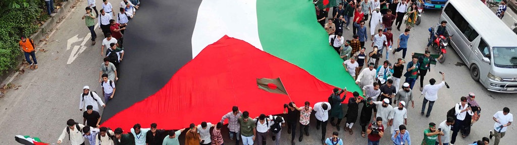 Demonstranten schwenken die Nationalflagge Bangladeschs während einer Kundgebung am 5. September 2024 in Dhaka, einen Monat nach dem Sturz der ehemaligen Premierministerin Sheikh Hasina.