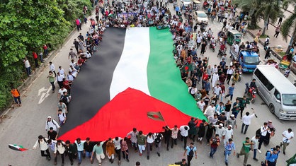 Demonstranten schwenken die Nationalflagge Bangladeschs während einer Kundgebung am 5. September 2024 in Dhaka, einen Monat nach dem Sturz der ehemaligen Premierministerin Sheikh Hasina.