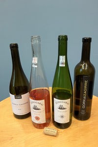 Vier Weinflaschen verschiedener Sorten und Marken stehen angebrochen auf einem Tisch.