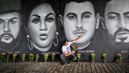 Archibild 2020: Çetin Gültekin legt seine Hand auf das Porträt seines Bruders, Gökhan Gültekin, unter der Frankfurter Friedensbrücke