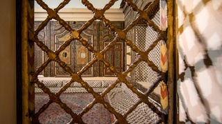 Das aufwendig mit Hand gearbeitete Damaskuszimmer in Dreseden durch eine Holzgittertür hindruch fotografiert.